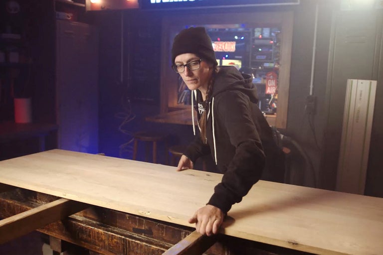 Kvinna hanterar träskiva i verkstad