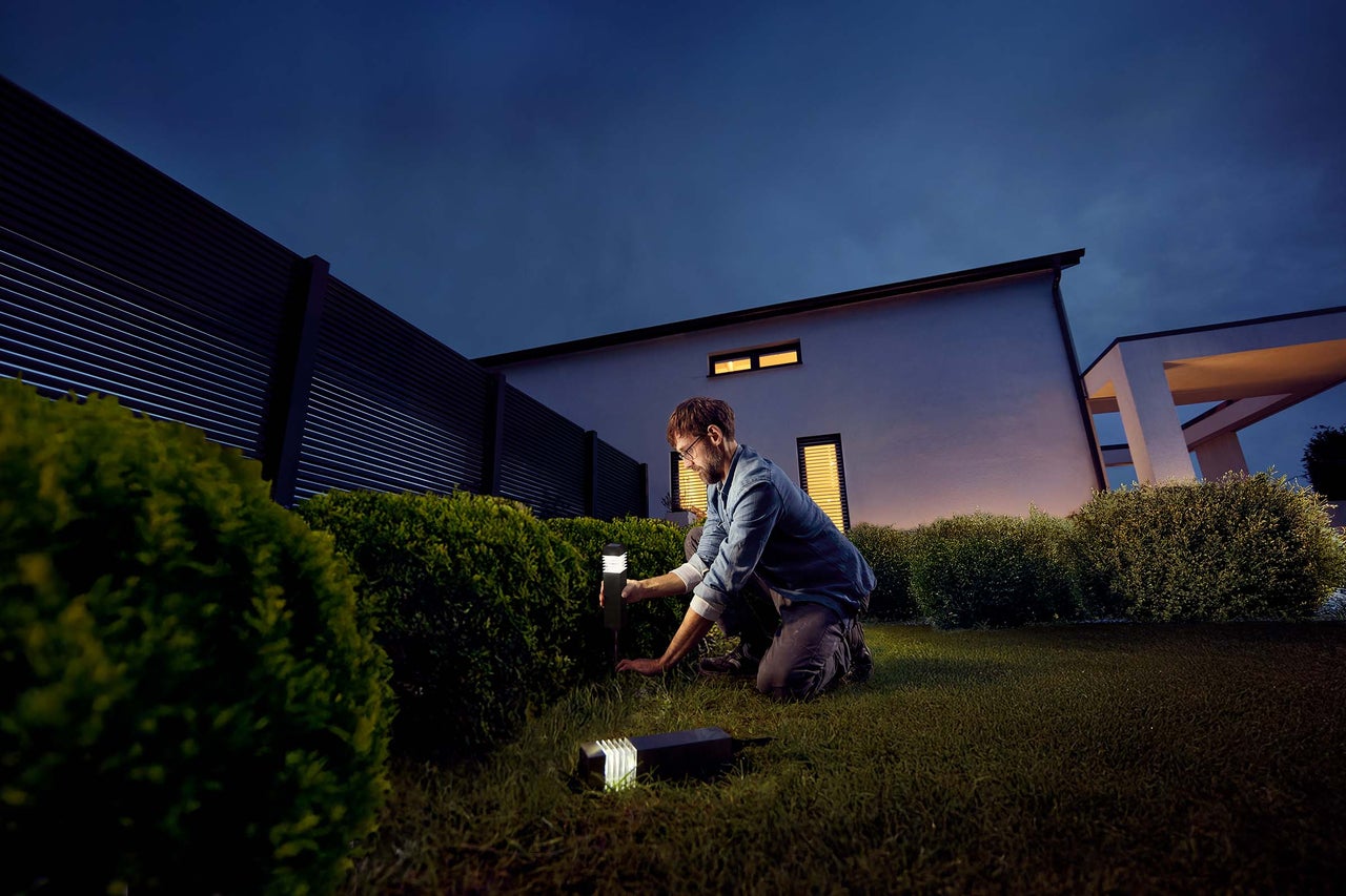 Man installerar trädgårdslampor i trädgården.