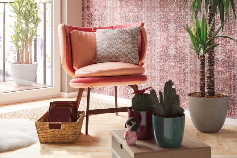 Vardagsrum med fåtölj, prydnadskuddar, krukväxter och dekorationer för en mysig atmosfär.