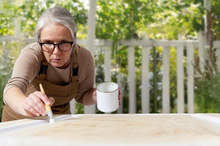 Kvinna målar trä med färg och pensel