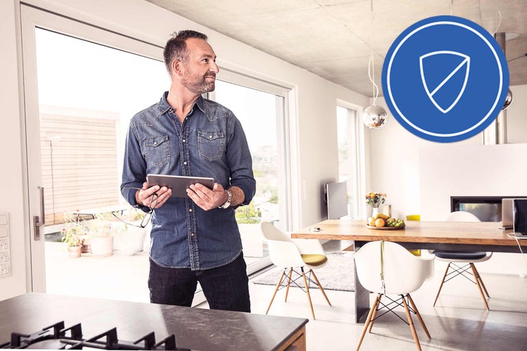 Man med surfplatta i ett modernt inrett vardagsrum med symbolen för skydd.
