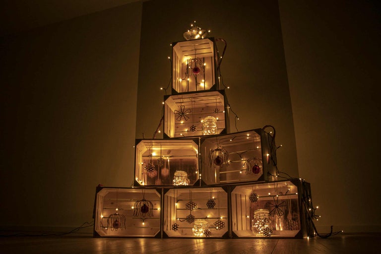 Dekorativ julgran gjord av trälådor med ljusslingor och ornament