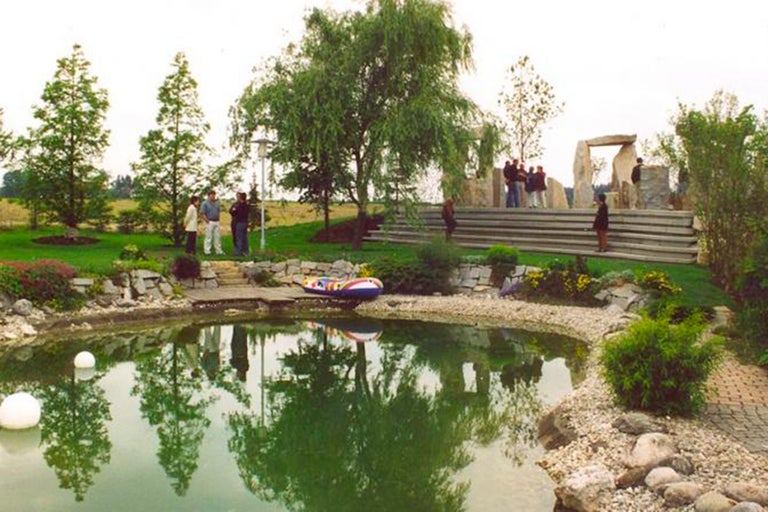 Landskapsarkitektur med damm, träd och stentrappa