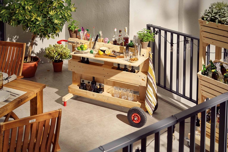 Fotografi av en träbar på en balkong, fylld med drycker och glas.