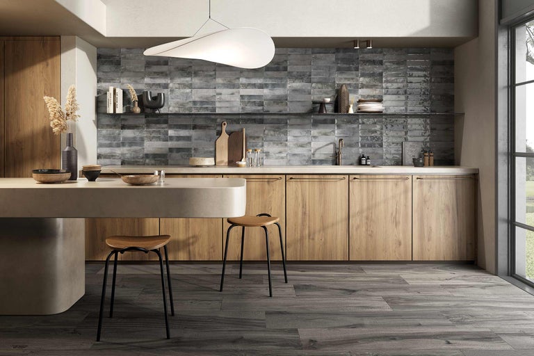 Ljust kök med träelement, grå kakel och moderna stolar
