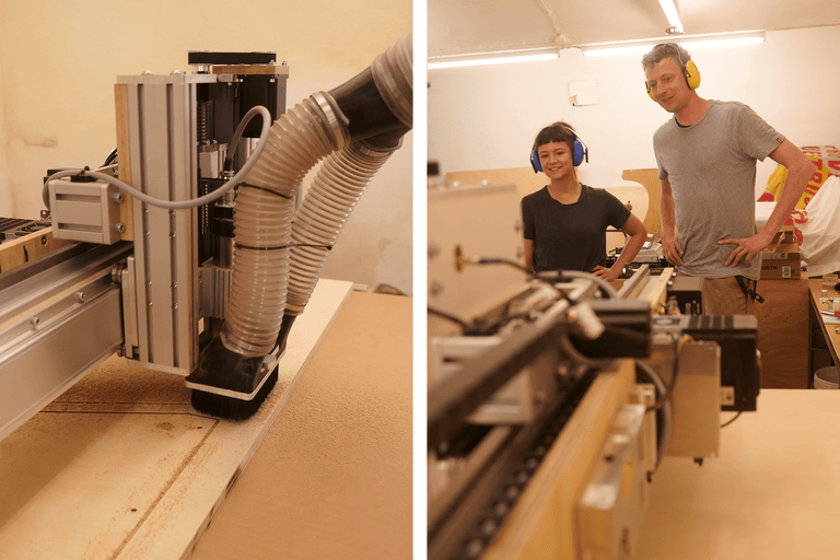 Datastyrd CNC-fräsmaskin som bearbetar trä. Två personer bär hörselskydd.