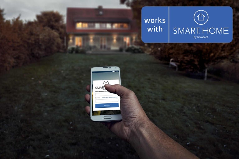 En smarttelefon i handen framför ett hus med texten "Works with Smart Home by Hornbach"