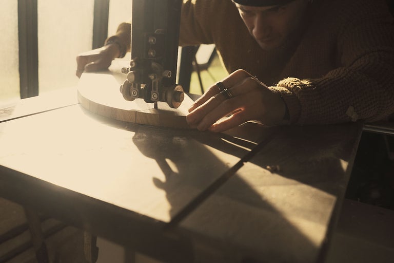 Hantverkare som arbetar med en bandsåg på en träbit.