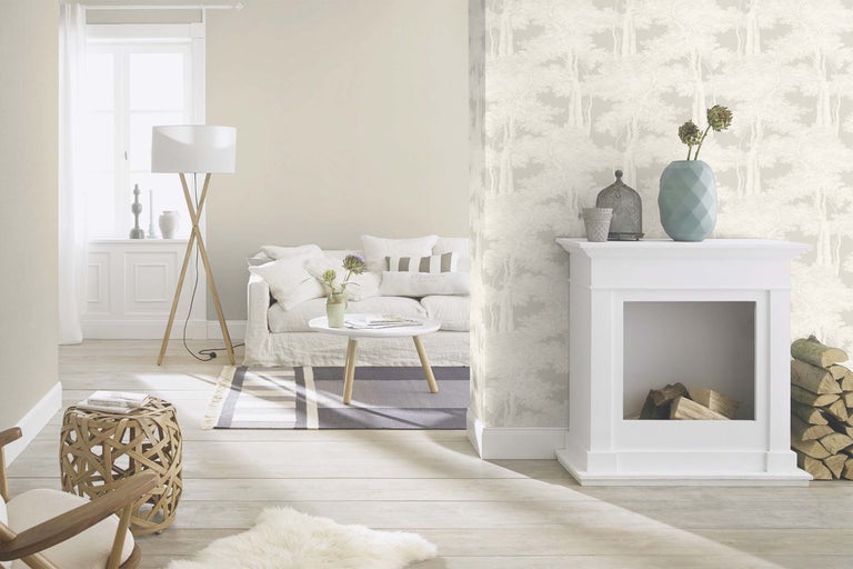 Vardagsrum med soffa, bord, golvlampa, öppen spis och tapet med skogsmönster