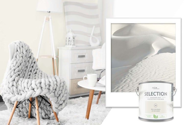 Miljöbild med stol, filt, lampa, byrå, bord, tavla och färgburk