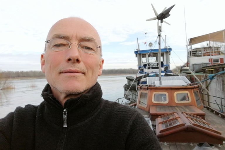 Man framför en husbåt med solpaneler och vindkraftverk