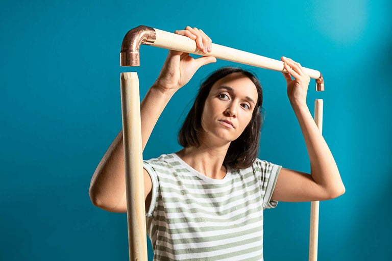 Kvinna monterar rörkonstruktion med trä- och kopparförbindelser