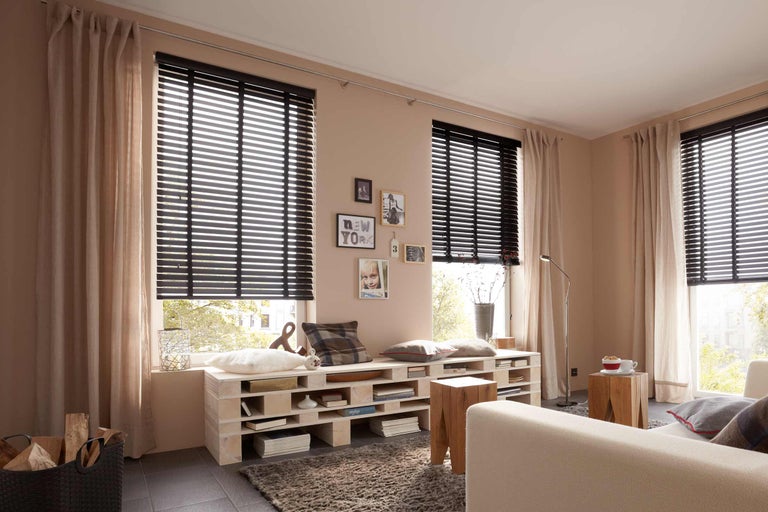 Vardagsrum med träpersienner, gardiner och pallmöbler