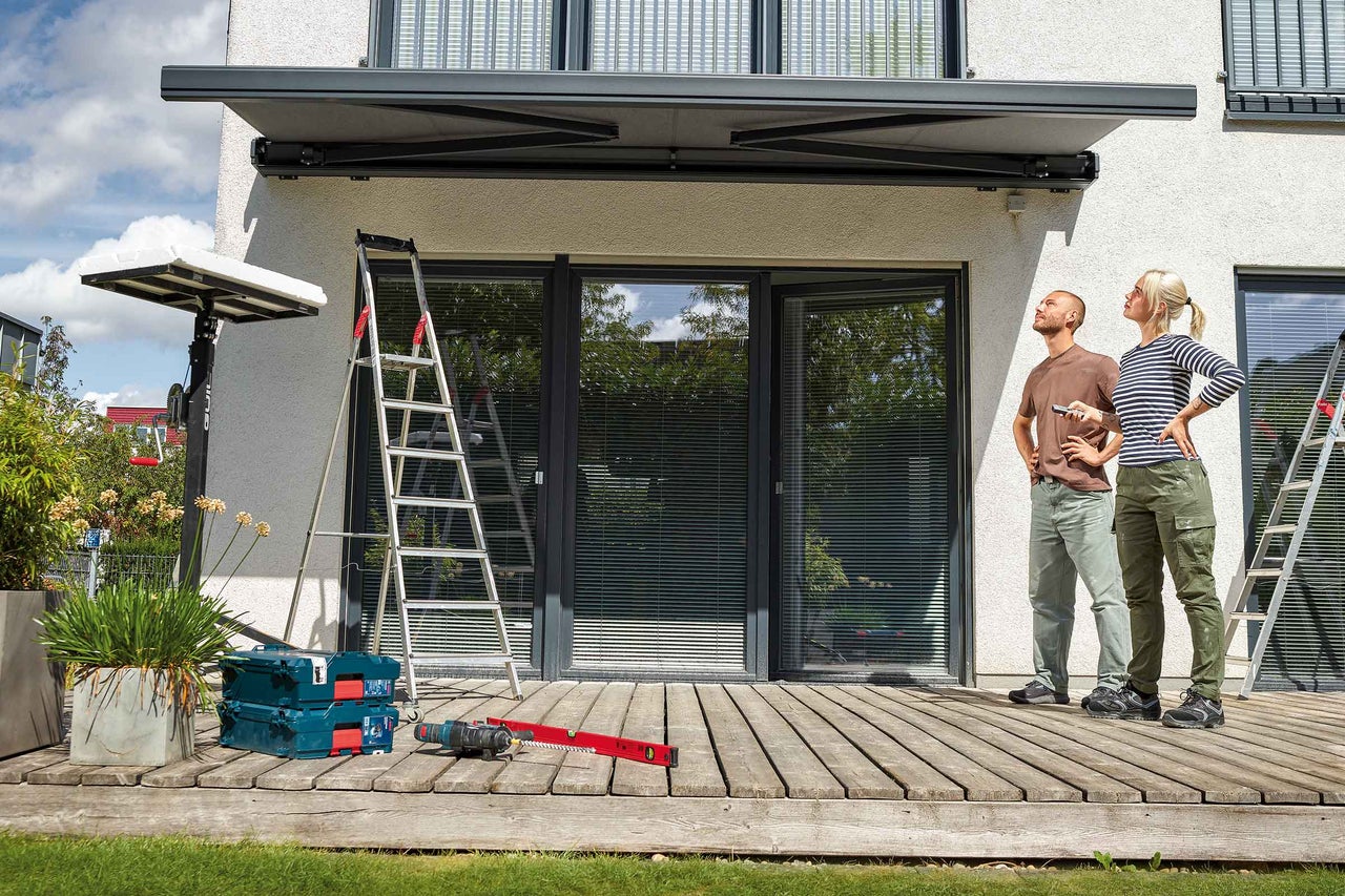 Terrass med trägolv, träbord med två stolar, bambu och solsegel