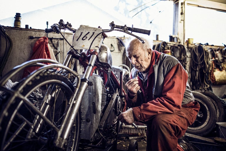 En man reparerar en motorcykel i en verkstad.