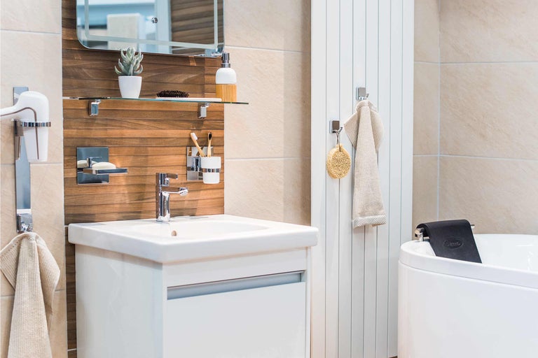 Ljust badrum med handfat, spegel, handdukstork och badkar.