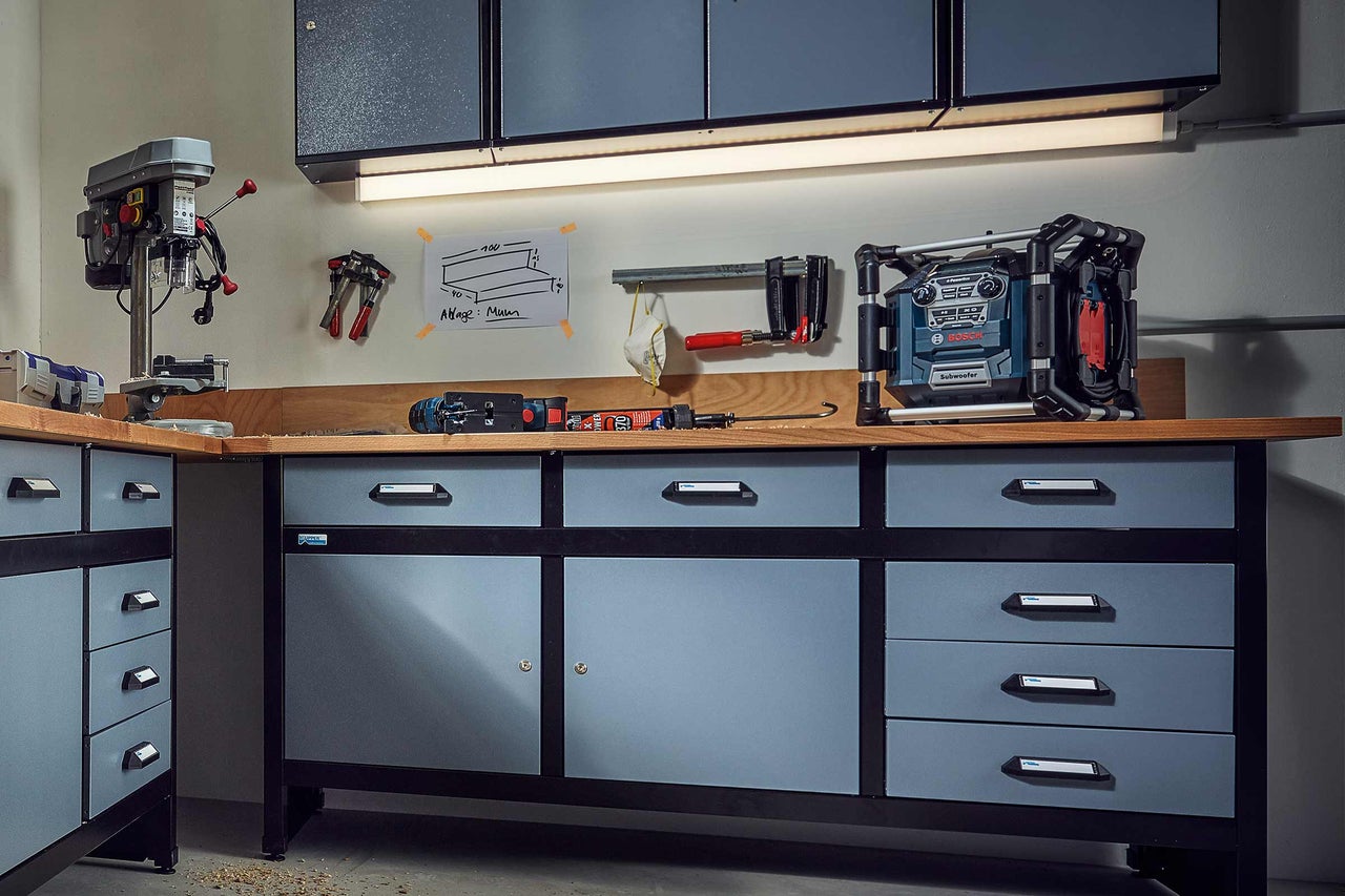 Arbetsbänk med lådor och verktyg, inklusive borrmaskin, sticksåg och radio