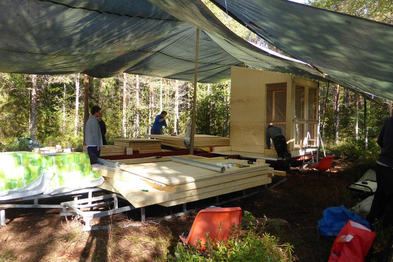 Byggande av en träkoja i skogen med träpaneler och presenningar