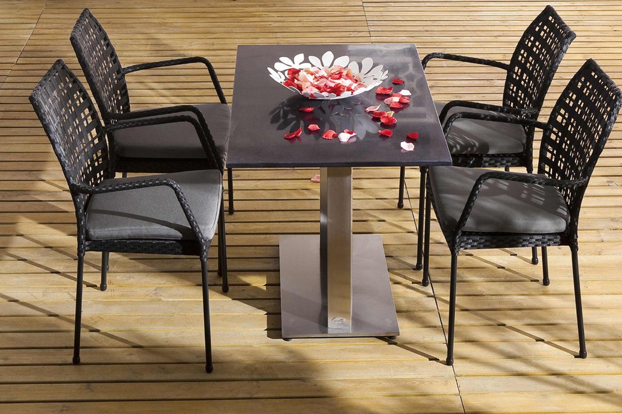 Trädgårdsbordgrupp med fyra rottingfåtöljer och ett bord med en skål med blomblad