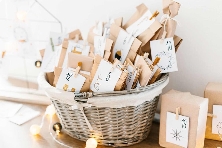 Fylld adventskalender med numrerade paket i en flätad korg.