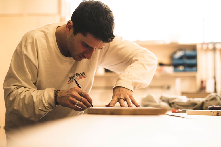 En man ritar med en penna på en träbräda.