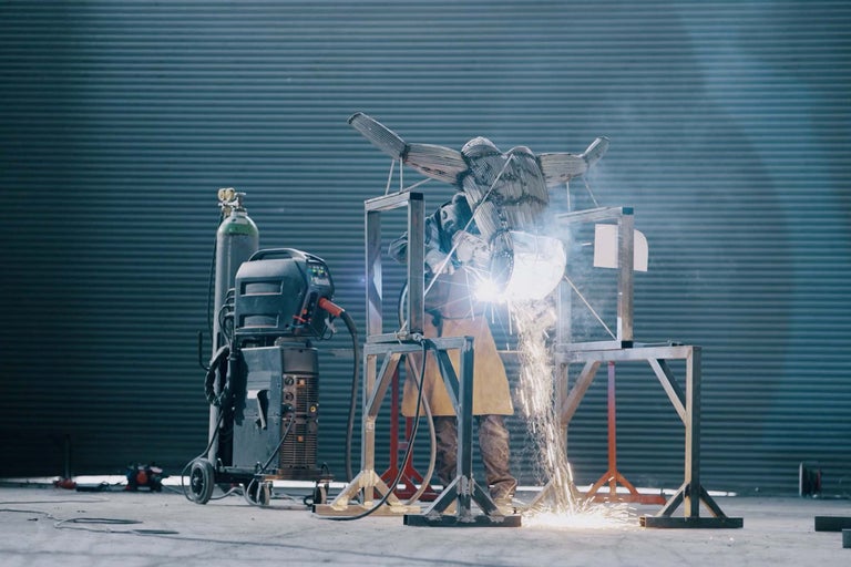 Svetsare som arbetar på en metallskulptur med svetsutrustning