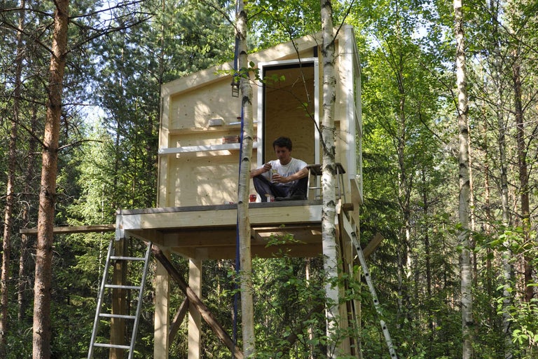 Trähus med stege i en skog med en man