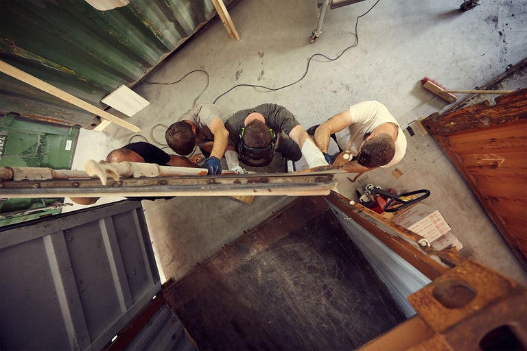 Ovanifrån ser man tre hantverkare som arbetar med ett byggprojekt