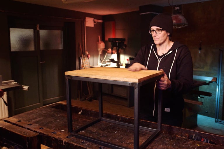 Fyrkantigt sidobord med träskiva och metallram i verkstad