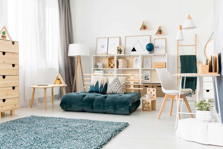 Ljust vardagsrum med blågrön madrass, hyllor och träelement