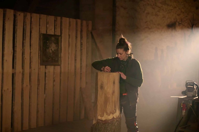 Kvinna bearbetar trädstam i verkstad