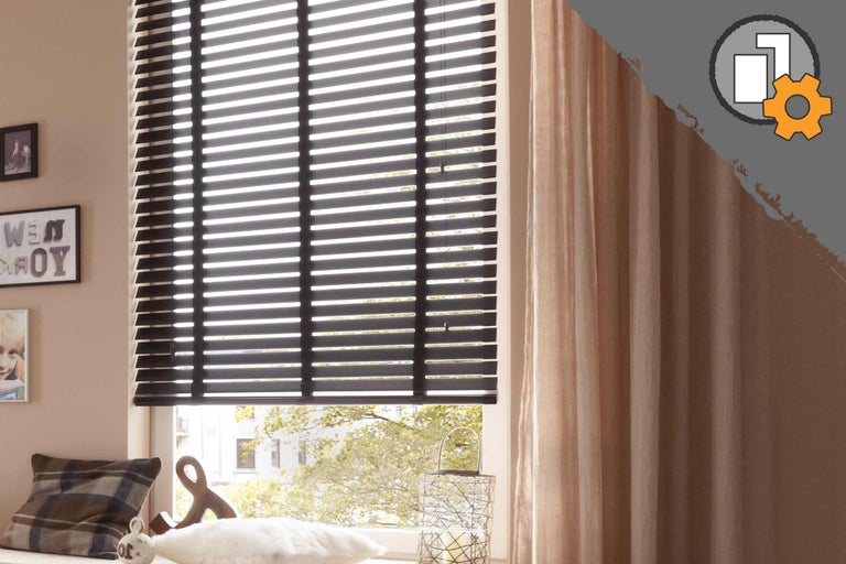 Rum med svarta persienner och gardiner vid fönstret.