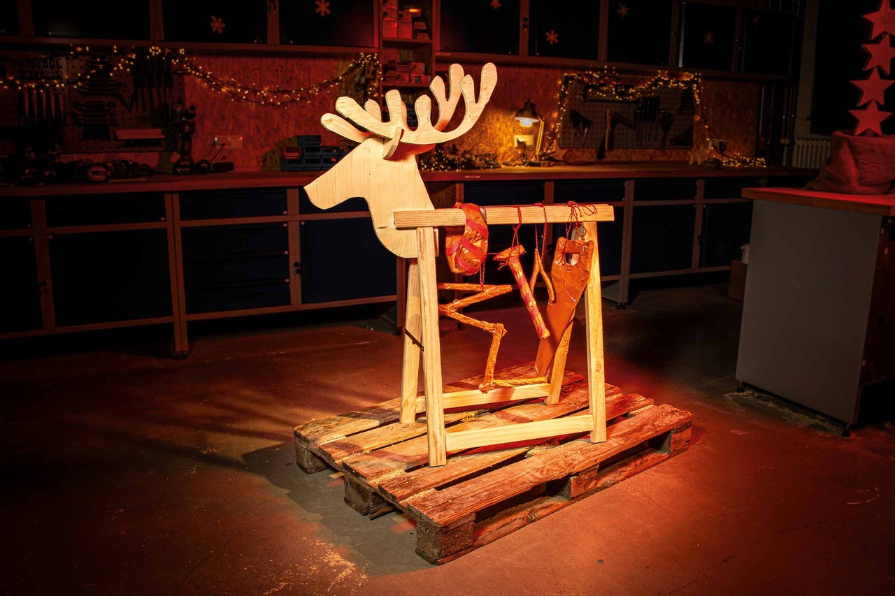 Trärenskulptur på en pall med verkstad i bakgrunden