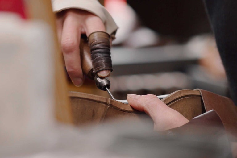 En person använder en syl för att sy läder