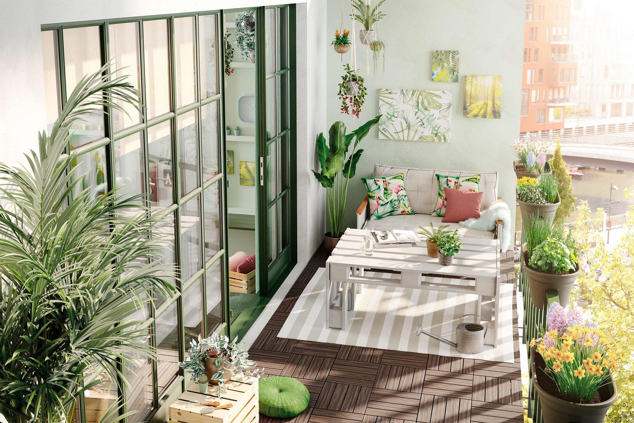 Dekorerad balkong med möbler, växter och trägolvplattor.