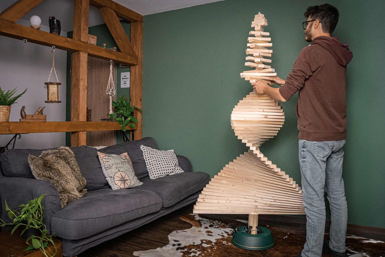 Man bygger en julgran i trädesign i vardagsrummet.
