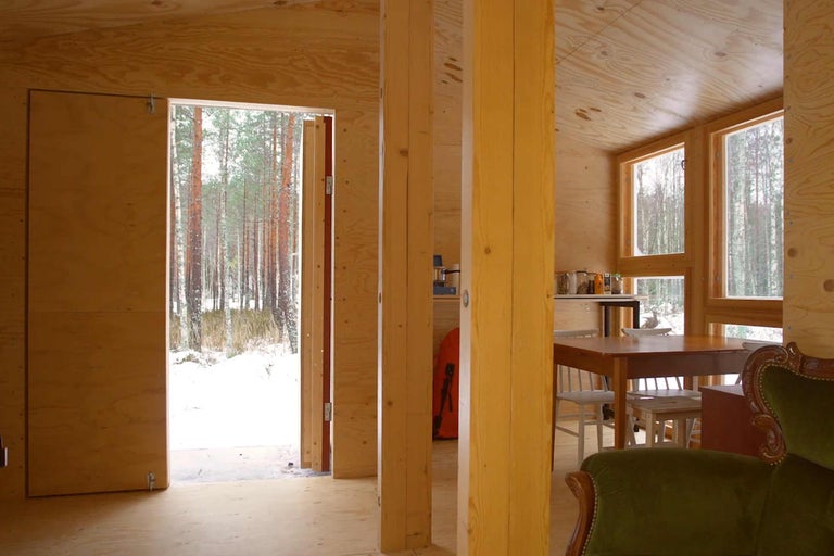 Interiör av ett trähus med utsikt över en vintrigt skog.