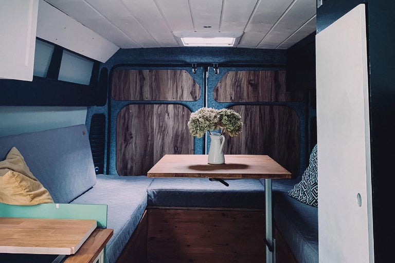 Interiör av en ombyggd skåpbil med säng och bord