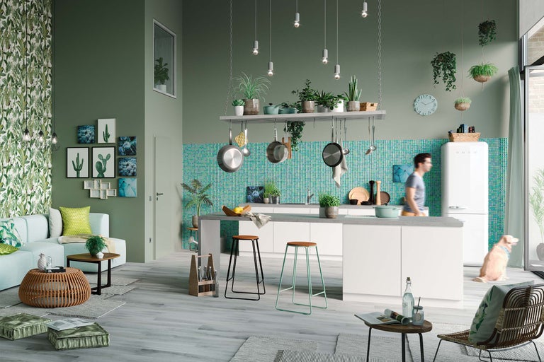 Ljust, rymligt kök med köksö, barstolar, hängande växter och dekorationer