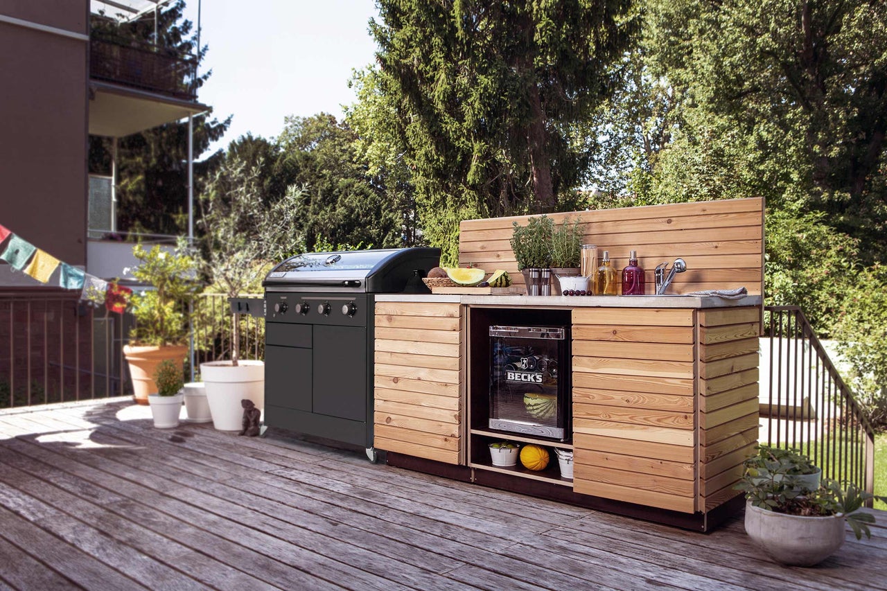 Utekök med grill, diskho och kylskåp på en träterrass