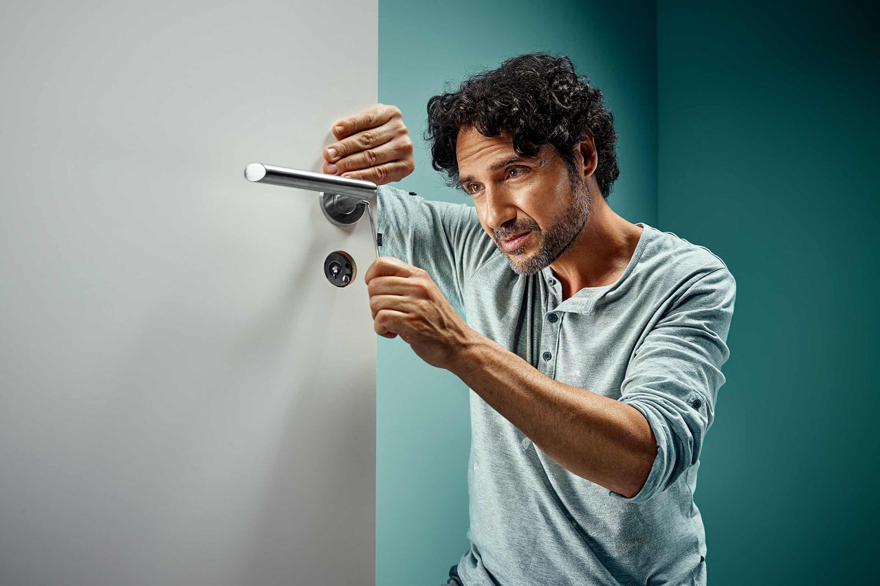 Man installerar en innerdörr med ett dörrhandtag i rostfritt stål