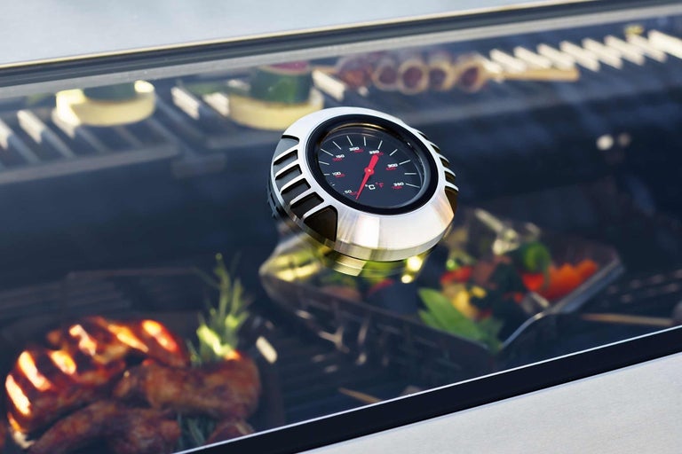 Närbild av en grilltermometer med mat i bakgrunden