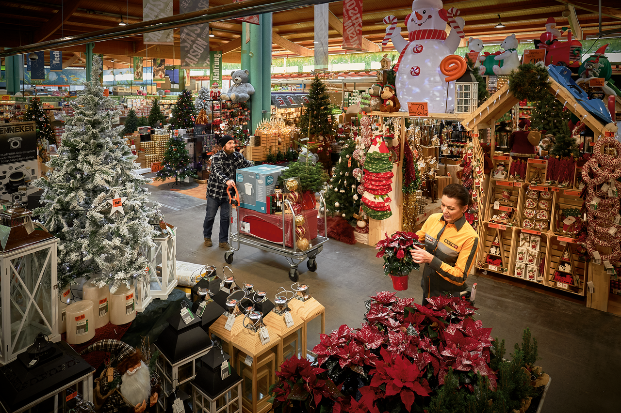 Interiörbild av en Hornbach-butik med juldekorationer, inklusive julgranar, lyktor och dekorationer, samt kunder och anställda.