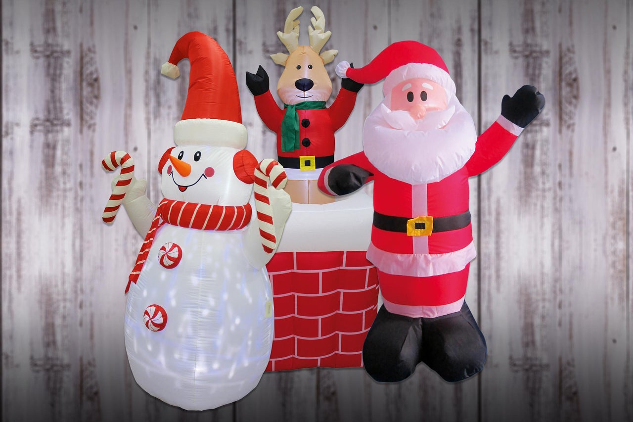 Uppblåsbar juldekoration med snögubbe, ren och jultomte framför en trävägg
