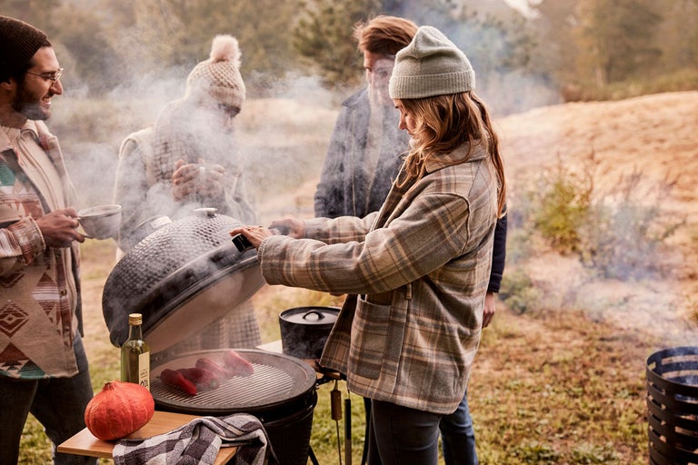 Grupp människor grillar utomhus med en keramisk grill, inklusive pumpa och drycker