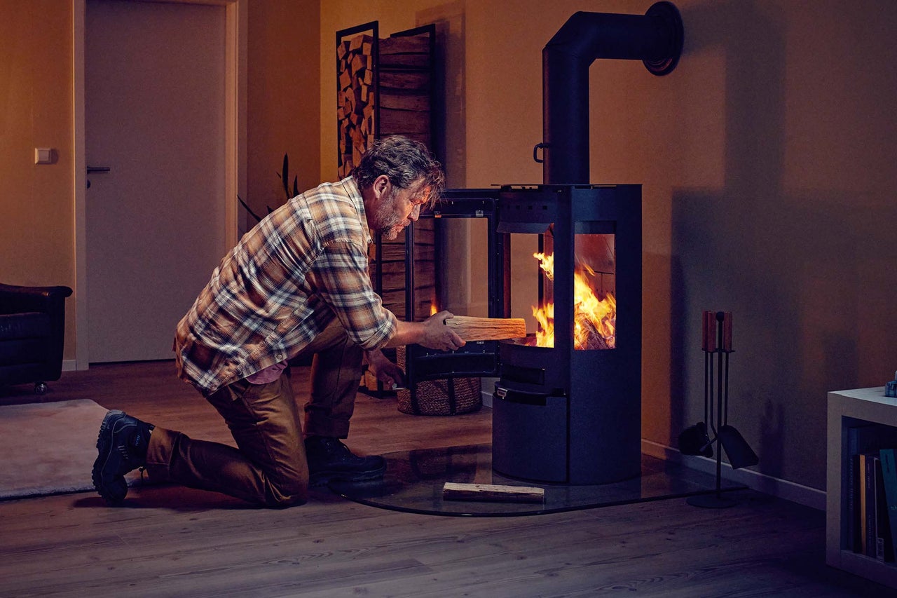 Man lägger ved i en braskamin i vardagsrummet
