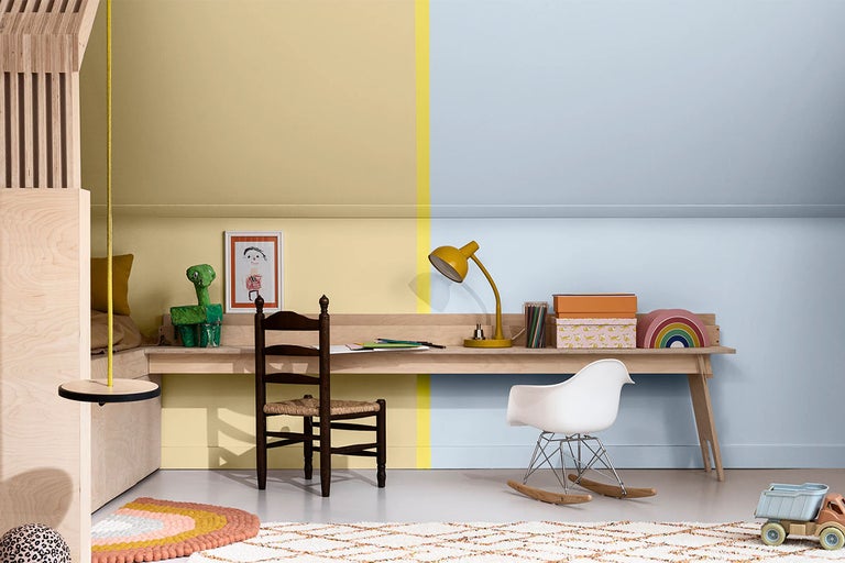 Barnrum med skrivbord, stolar och leksaker målade i gult och blått.