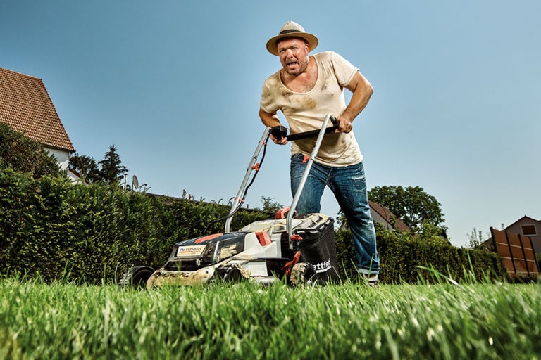 Man klipper gräs med en gräsklippare av märket Pattfield
