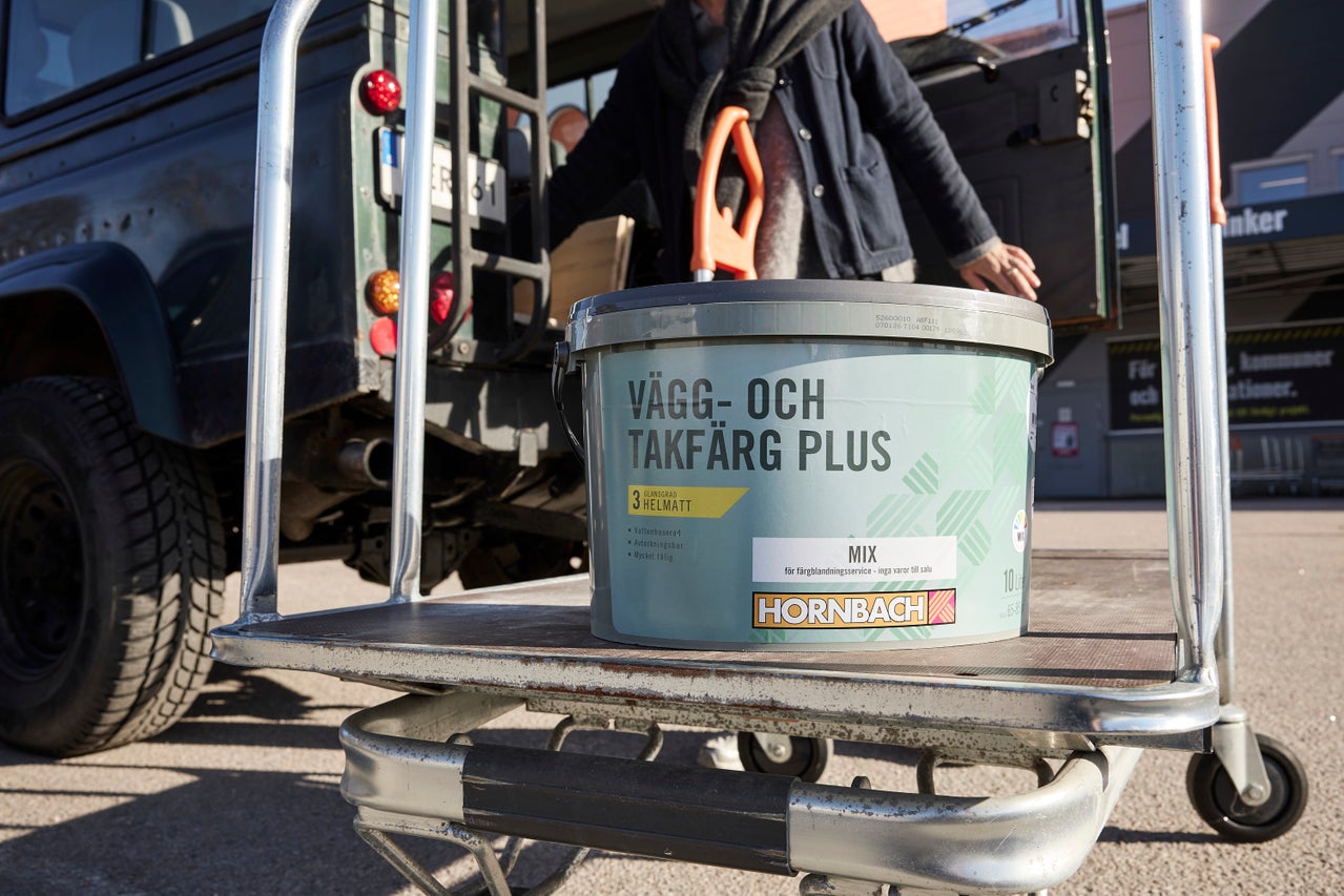 10 liters hink med helmatt Hornbach vägg- och takfärg Plus på en transportvagn av metall framför en terrängbil.