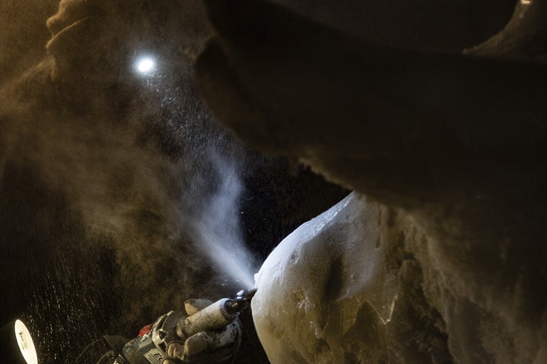 Närbild av en person som arbetar med en skulptur med ett multifunktionellt verktyg.